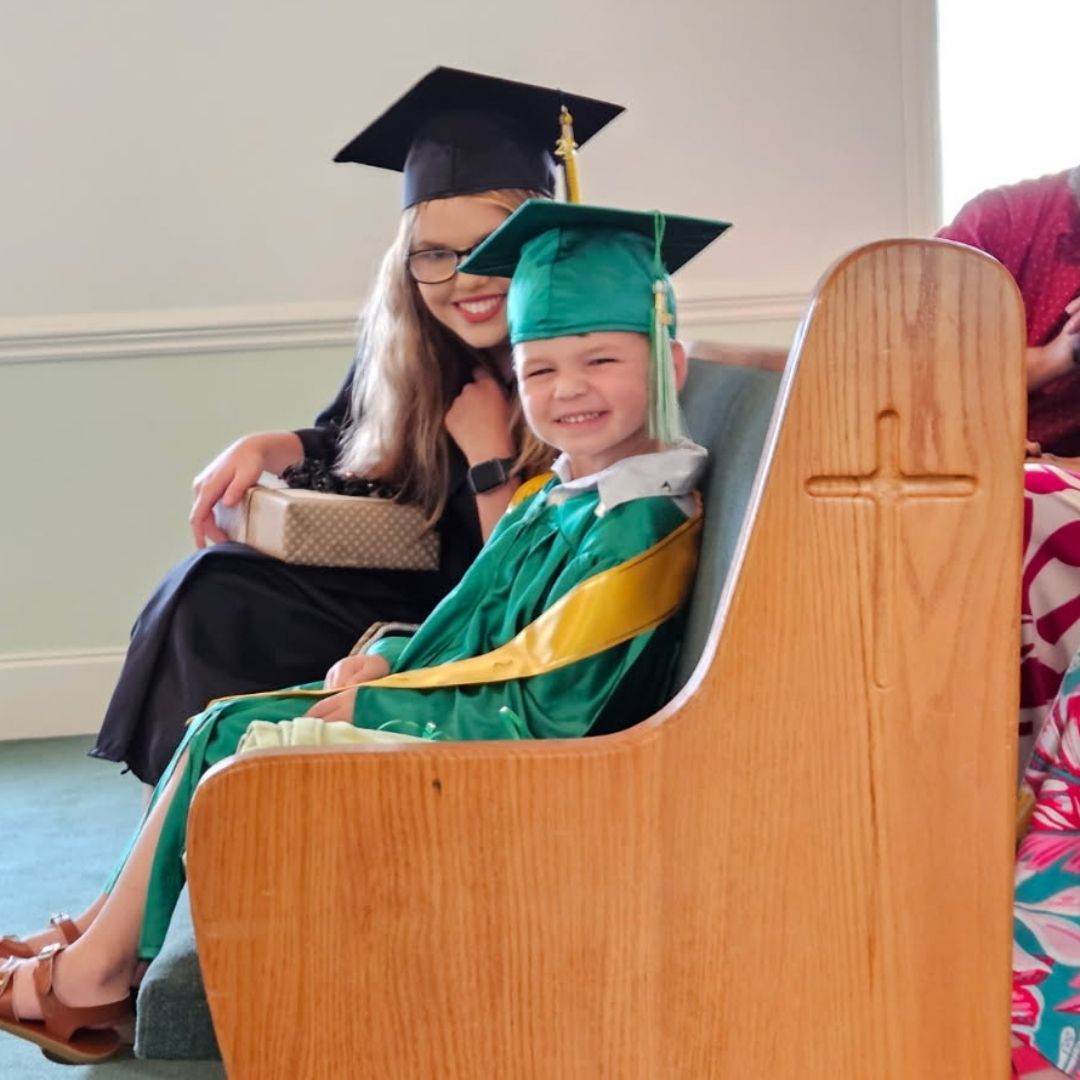 Two children in graduation caps and gowns at church